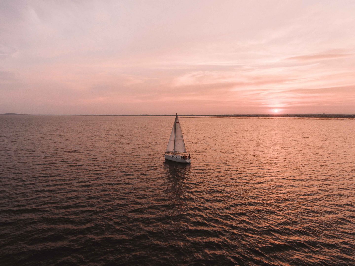 un bateau des Glénans avec un coucher de soleil sur l'étang de Thau